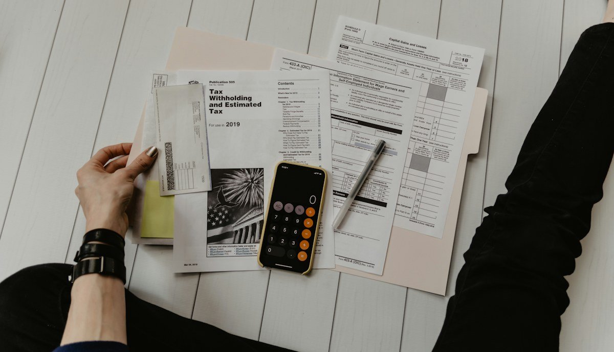 Persona revisando sus finanzas y organizando documentos sobre una mesa